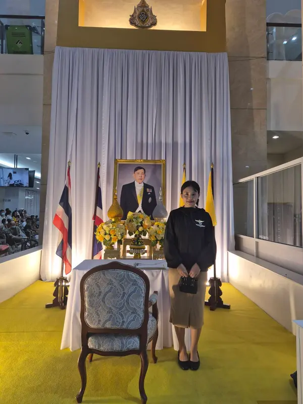 Standing beside the well-wishes signing table, in front of a portrait of His Majesty the King, at the Police General Hospital