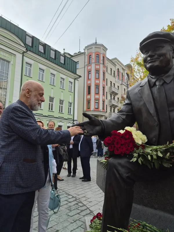 A man lays roses beside a bronze statue during the visit